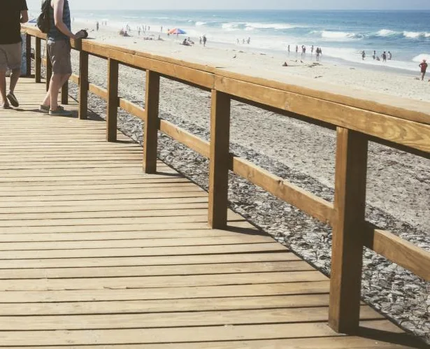 Timber boardwalk with a wooden guard rail running toward the shoreline