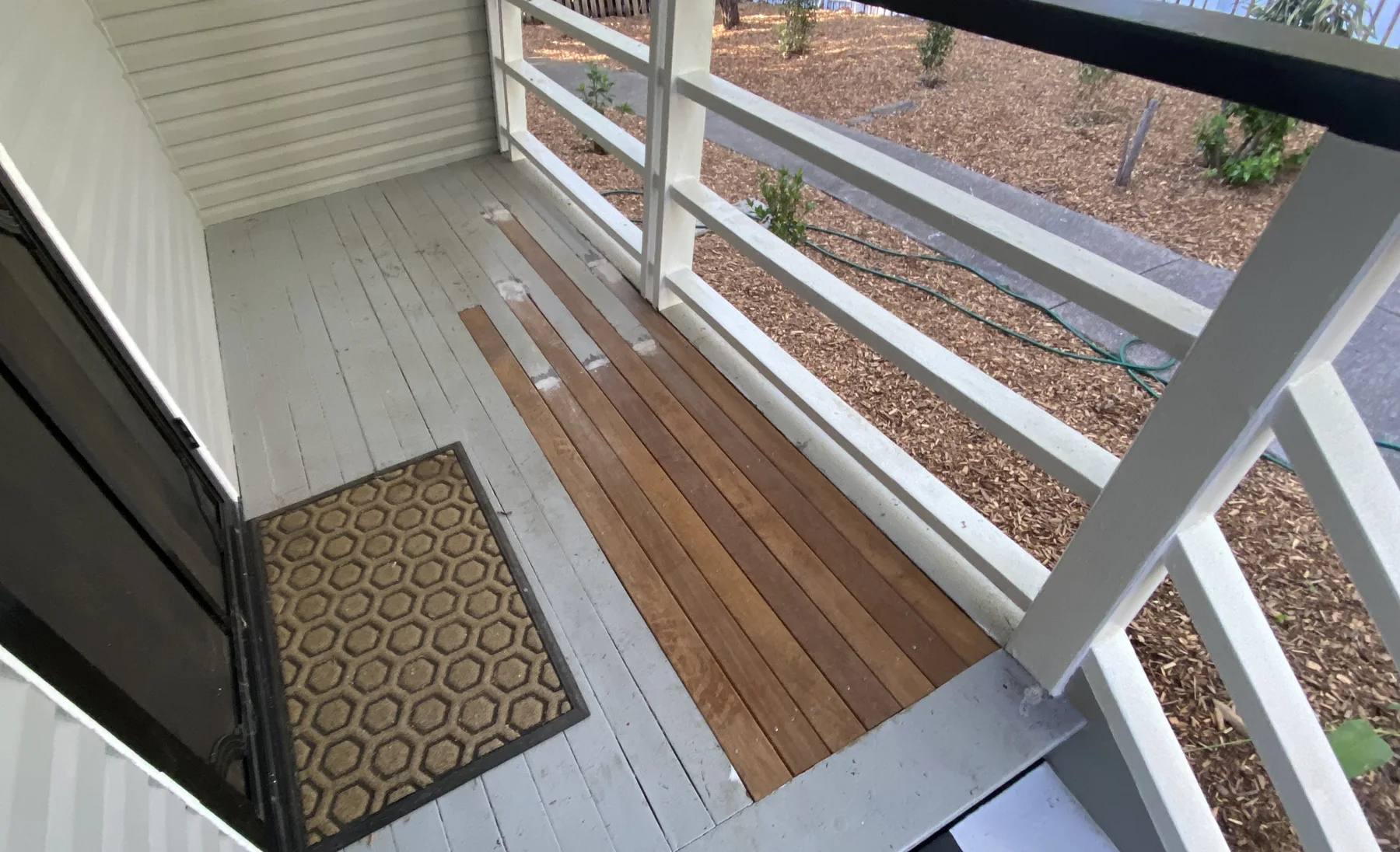 Rebuilt balcony deck with a fresh white rail and new timber flooring