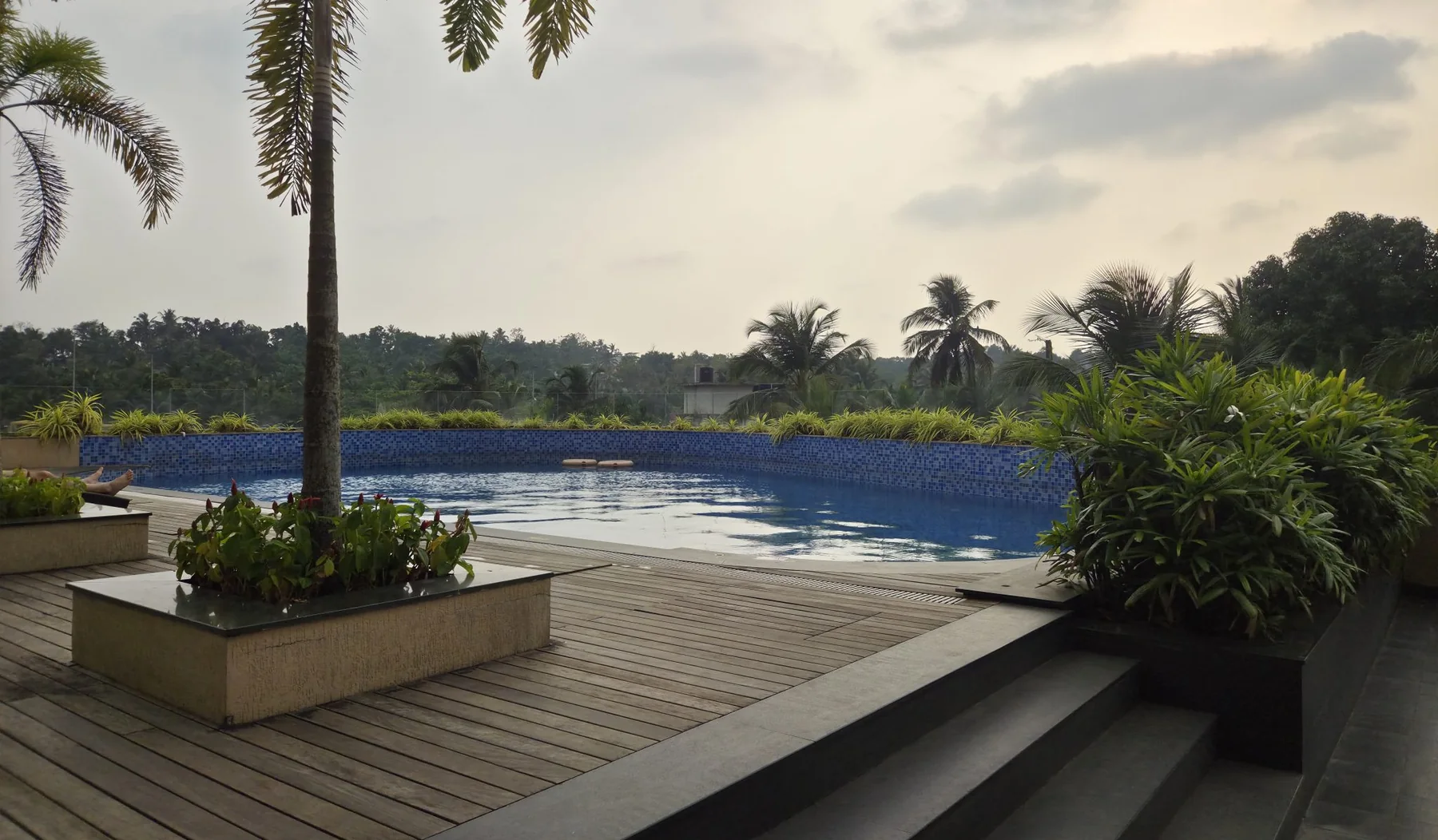Wide deck with steps running down beside a swimming pool at dusk